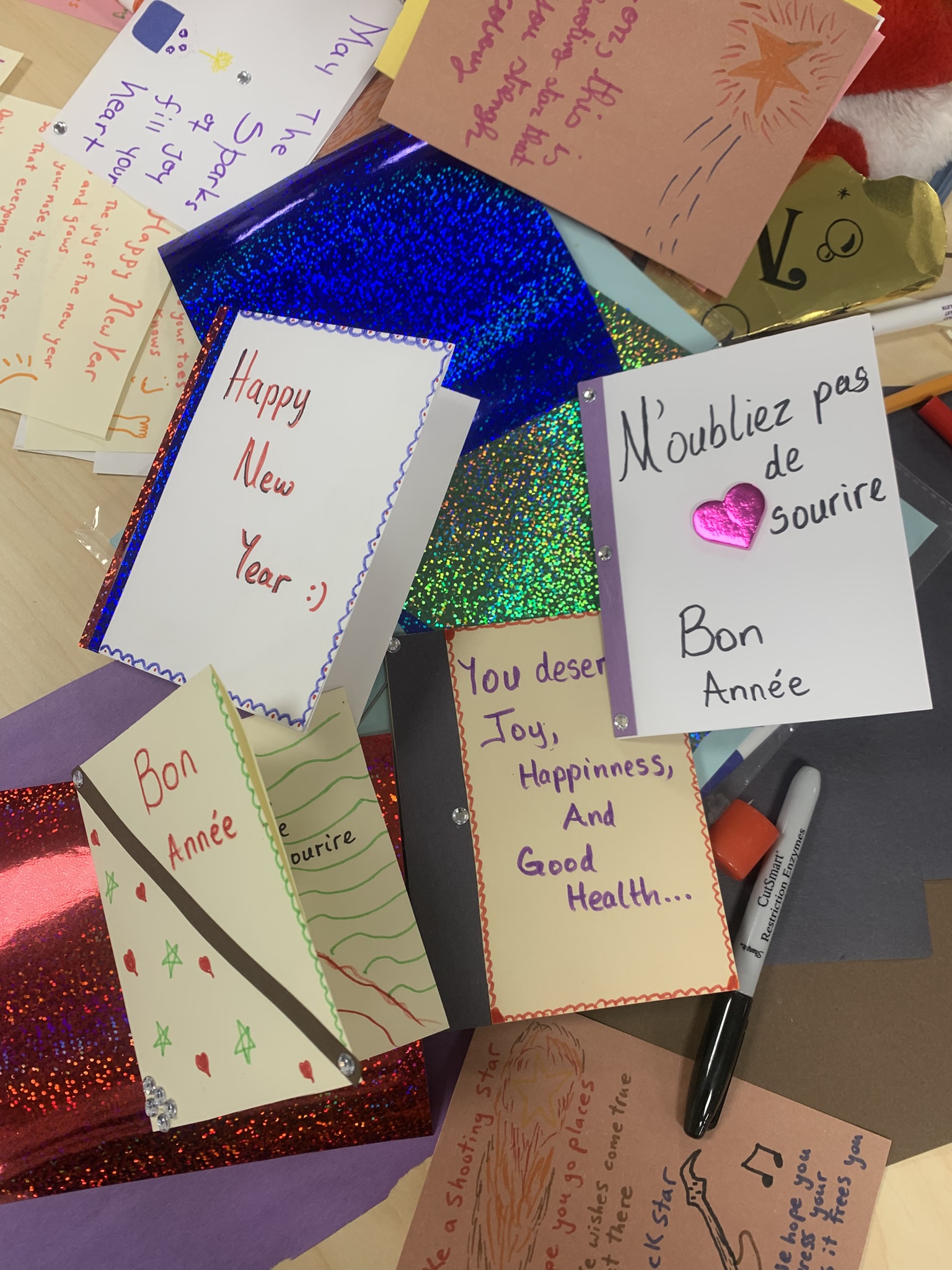 Multiple colorful cards spread on table including 'Happy New Year' messages