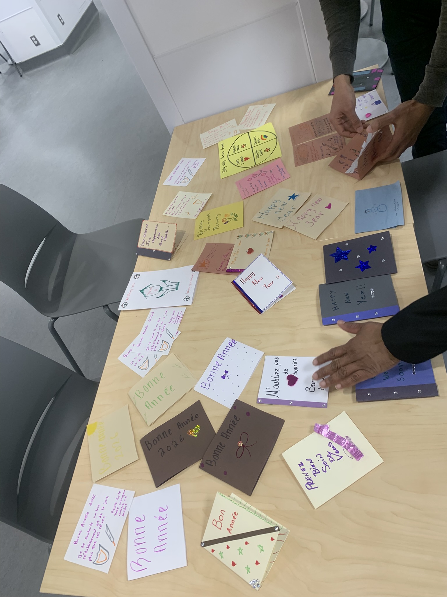 Overhead view of volunteers' hands sorting through dozens of completed cards on wooden table