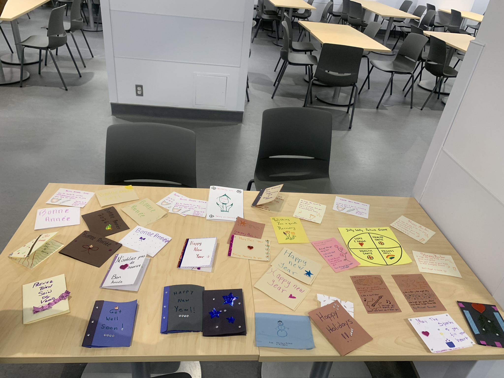 Wide view of library table displaying the full collection of colorful handmade cards ready for distribution